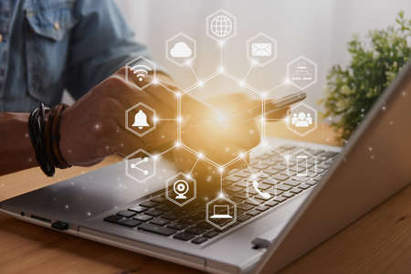 Casual Businessman Touching Smart Phone or Mobile Phone Screen by Finger on Laptop Computer and Hexagonal Social Media Communication Sign Search Icon,Position Pin,Wifi,Cloudの写真素材