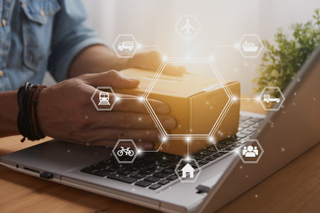 Hand of Casual Businessman or Entrepreneur Catch Parcel or Box on Laptop and Hexagon Logistic or Transportation Icon. SME Online Business and E-commerce Concept for Work at Homeの写真素材