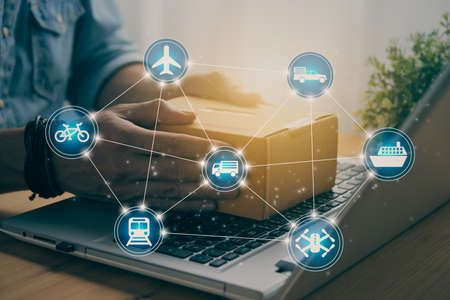 Hand of Casual Businessman or Entrepreneur Catch Parcel or Box on Laptop and Hexagon Logistic or Transportation Icon. SME Online Business and E-commerce Concept for Work at Home in Vintage Toneの写真素材