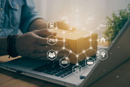 Hand of Casual Businessman or Entrepreneur Catch Parcel or Box on Laptop and Hexagonal Logistic or Transportation Icon. SME Online Business and E-commerce Concept for Work at Home in Vintage Toneの写真素材