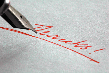 the word "thanks" written with red ink on white paperの写真素材