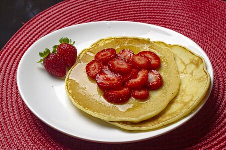 Homemade pancake with strawberries and syrup in the white plate