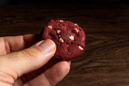 Hand holding a red velvet cookie with white chocolate.