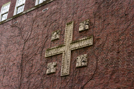 Medieval red brick wall with cement cross. Branches branch over the wall.の写真素材