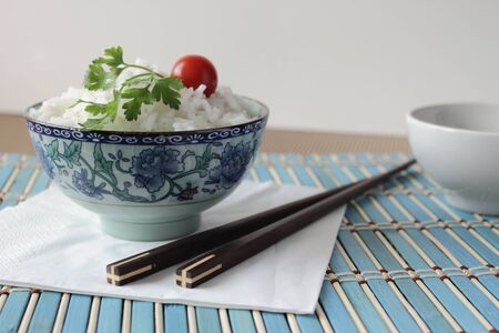 Oriental style composition with a cup of rice and chopsticks