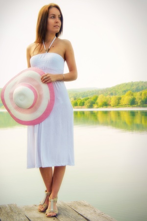 Beautiful young woman standing on edge of a pier and looking at the distanceの写真素材
