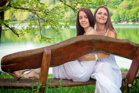 Two young woman are sitting on a bench in theirs holidaysの写真素材