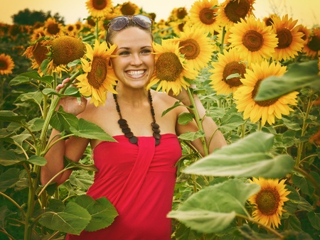 Vintage style photo from a beautiful young woman between sunflowers, noise added for a real film effectの写真素材