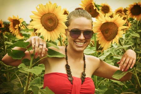 Vintage style photo from a beautiful young woman between sunflowers, noise added for a real film effectの写真素材