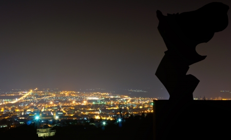 Silhouette from an angel statue, the City of Pecs in the background at night time This Photo was taken from the Mecsek mountain in Hungary の写真素材