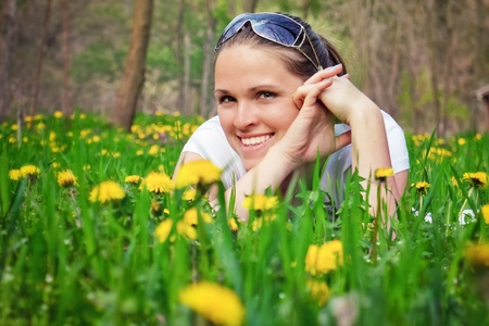 Beautiful woman lying on the ground, between spring flowersの写真素材