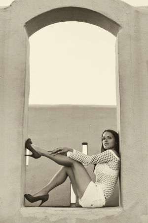 Beautiful young woman sitting in a big windowの写真素材