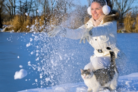 beautiful girl playing with a cat, and throw snow in to the airの写真素材