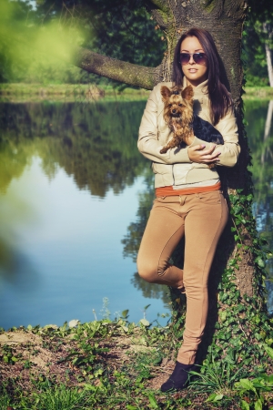 Beautiful young woman standing in a park with her dogの写真素材