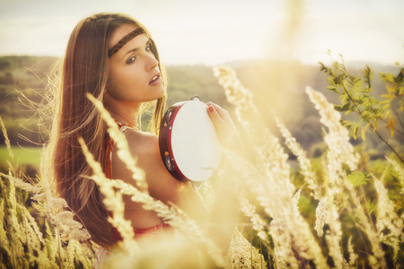 Beautiful young women playing in tambourine in autumnの写真素材