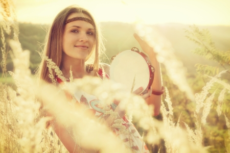 Beautiful young women playing in tambourine in autumnの写真素材