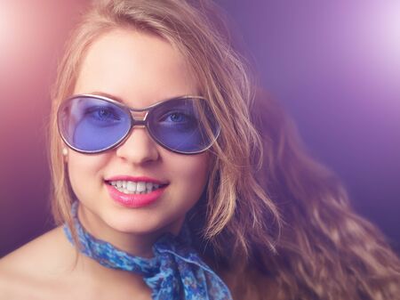 Young cheerful girl with party lights, in old fashioned retro sunglasses and scarfの写真素材