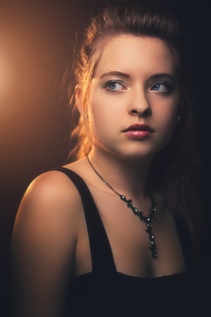 Close up photos from a beautiful young girl in a dark room at night, warm backlight in the backgroundの写真素材