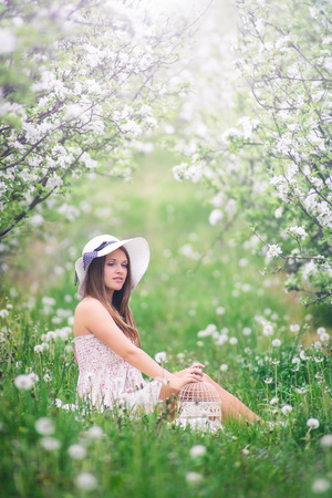 Beautiful young girl sitting in the garden at fruit flowering in springの写真素材