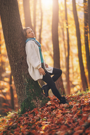 Young woman in the autumn forest, beautiful sunlight in the backgroundの写真素材