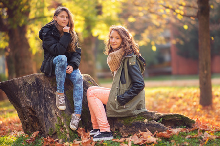 Two young girl in the city park at autumnの写真素材