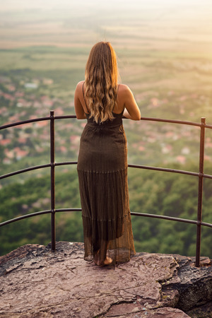 Young woman standing on the view point of the famous place called "Jacob's mountain" in Hungary, at sunriseの写真素材