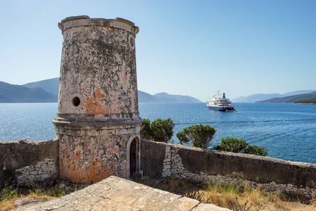 Old lighthouse with a luxury ship in the background, in Kefalonia, Ionian Islands, Greeceの写真素材