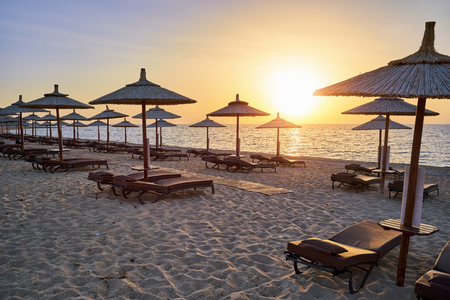 Canopy beds on the sandy beach in the sunriseの写真素材