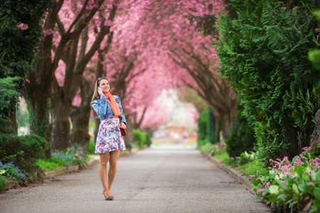 Young woman talking with her phone in a beautiful park at spring blossomの写真素材