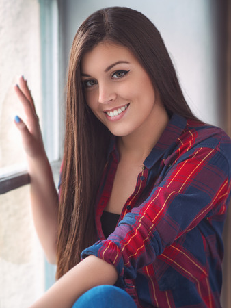 Beautiful young woman at the windowの写真素材