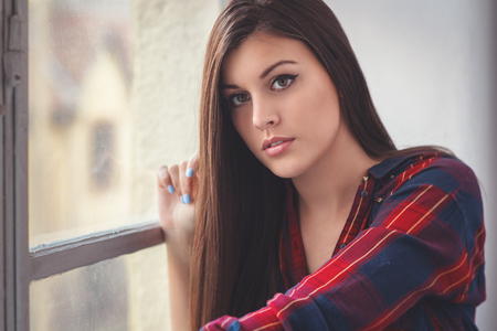 Beautiful young woman at the windowの写真素材