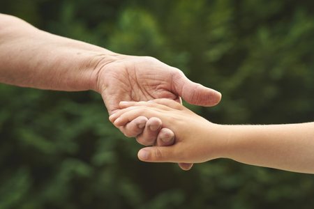 Hand in hand. Old woman holds her young grandchild's handの写真素材
