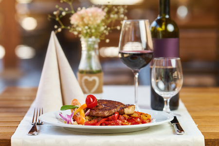 Pork meat with Ratatouille and red wine in a restaurantの写真素材