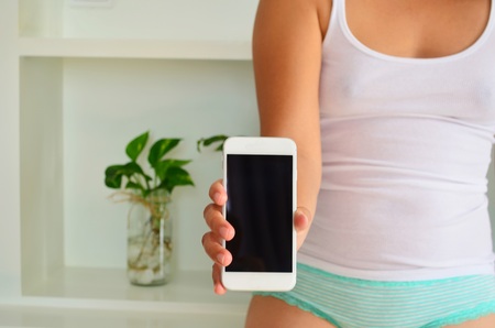 Beautiful woman in underwear is holding a phone in her hand.の写真素材