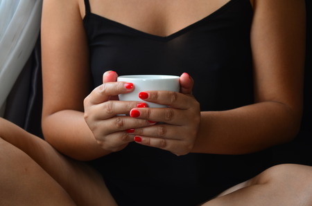 Beautiful woman is holding a cup of coffee in her hands.の写真素材
