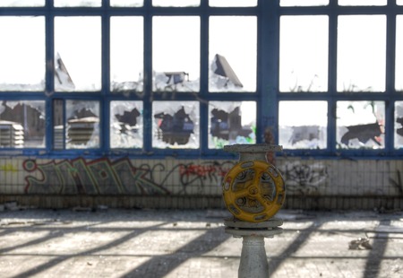 Tube and a yellow valve in an old hall with broken windowsのeditorial素材