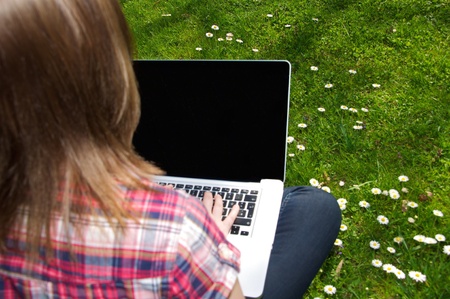 Woman surfing with her laptop in the gardenの写真素材