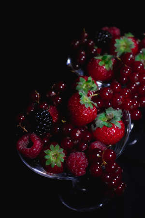 Different red fruits in a glass reflecting in a mirror, strawberries, berriesの写真素材