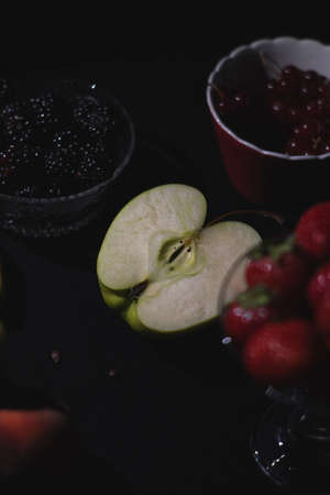 Different fruits together on black dark background, berries, banana, apple, raspberry, cranberryの写真素材