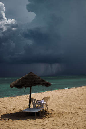 Mediterranean Sea with powerful storm in the background, light blue transparent water, sunbed with umbrellaの写真素材