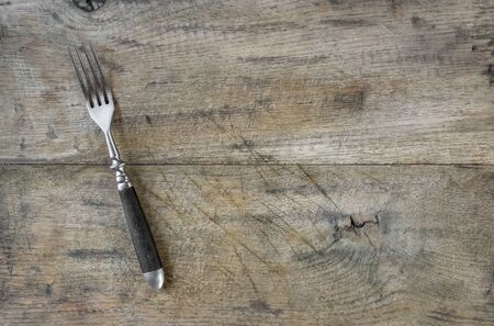 Old fork on wooden chopping boardの写真素材