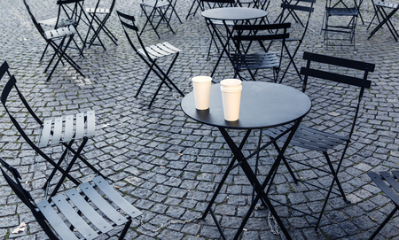 Chairs and tables scattered on pavement on early morningの写真素材