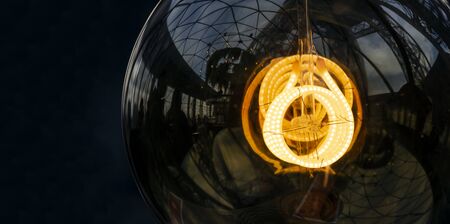 Close up on fancy, spiral, filament of a glowing light bulb