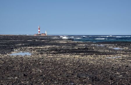 Rocky coast leading to El Toston Lighthouse in Fuerteventura Island