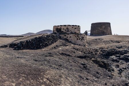 Not working lime kiln in front. Behind is old coastal fort called Castillo de El Toston in El Cotillo, Fuerteventura Islandの写真素材