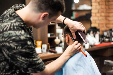 Razor in hands of professional barber. Hairdresser shaving man's neck with a straight razorの写真素材