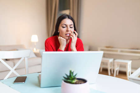 Worried young woman using laptop, feeling nervous passing online exam or distance graduation test on...