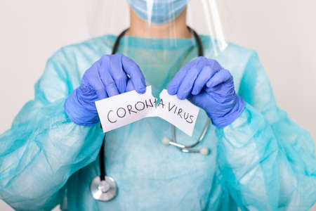 Concept of coronavirus quarantine. Covid - 19. Novel coronavirus (2019-nCoV).Doctor with a stethoscope Tear the paper with the word coronavirus.の写真素材