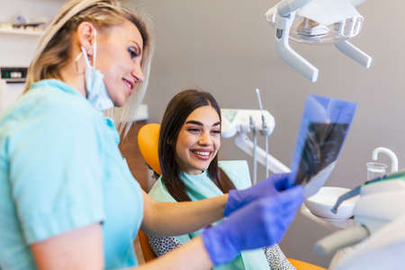 Jaw scan is being explained by the dentist to the patient. . Wearing protective masks respecting the...