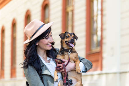 happy hipster woman playing with her dog on the street. stylish girl with funny dog resting, hugging and having fun, cute moments. space for textの写真素材